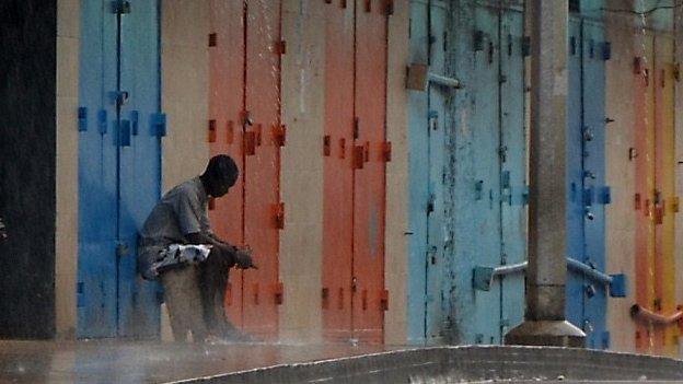 A lone man sits outside shops that were closed in Monrovia's West Point slum