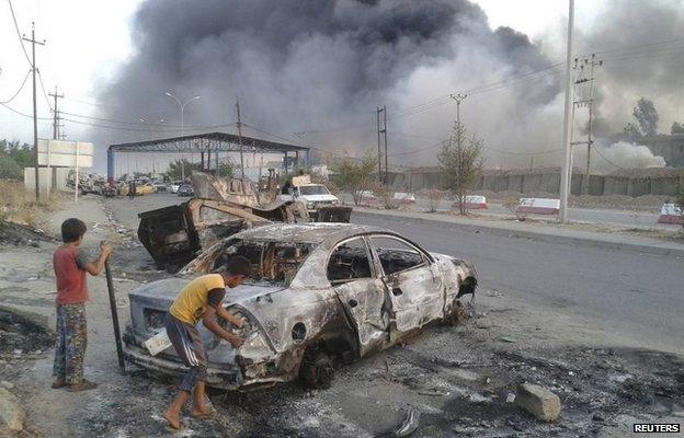 Children inspect a car destroyed during clashes between Isis fighters and Iraqi soldiers in Mosul (10 August 2014)