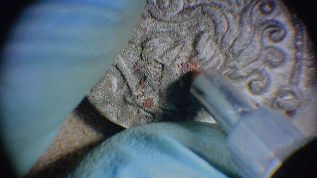 Microscope view of coin being cleaned