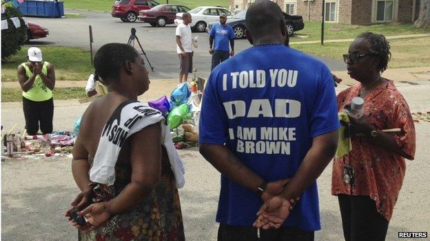 Michael Brown Sr., talks with well-wishers at a makeshift memorial set up to honour his son, Michael, who was fatally shot by a white police officer 13 days ago in Ferguson