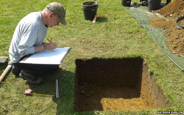 Archaeologist records details of an excavated pit