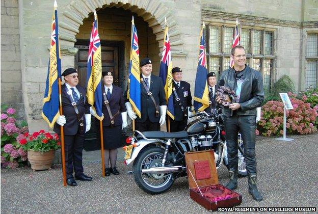 Veterans holding standards and a motorcyclist with a wreath