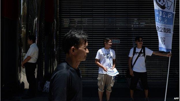 Volunteers display a banner and give out flyers on a street to raise awareness of an unofficial referendum in Macau on 24 August 2014.