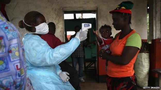 A Liberian Ministry of Health worker checks people for Ebola symptoms at a checkpoint near the international airport on August 24, 2014 near Dolo Town, Liberia.