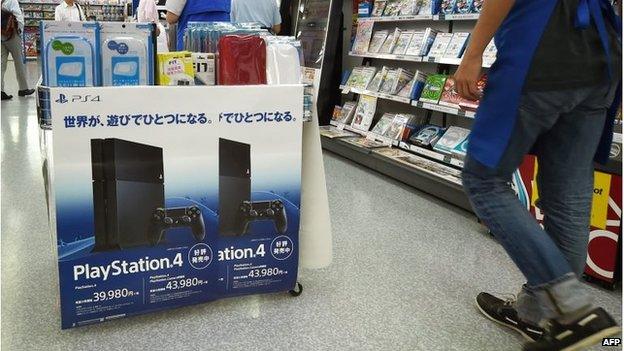 A customer walks past an electronics store display for Sony"s video game console PlayStation 4 in Tokyo on August 13, 2014.