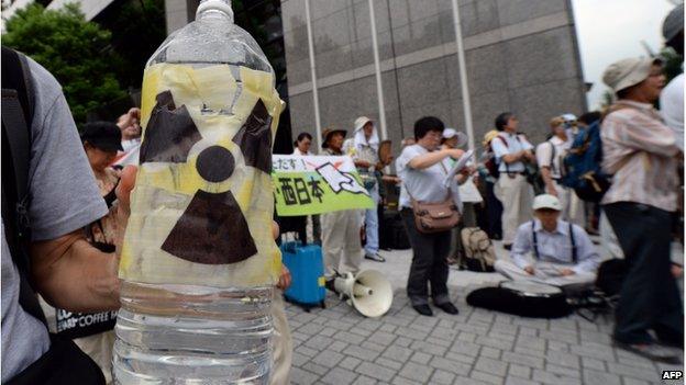 A demonstrator holds a bottle of water imitating radioactive-contaminated water from the Fukushima Daiichi nuclear plant during a protest in front of the Tokyo Electric Power Company (TEPCO) headquarters in Tokyo on 8 August 2014