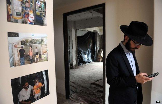 A rabbi stands alongside photographs of Rabbi Gavriel Holtzberg at Nariman (Chabad) House in the Indian city of Mumbai on August 26, 2014