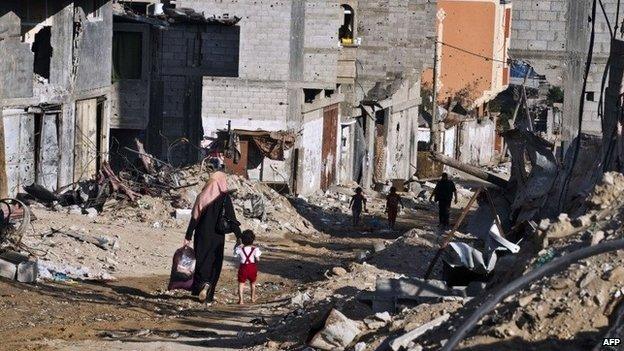 A woman and her child return to their home in Gaza City's Shejaiya district (27 August 2014)