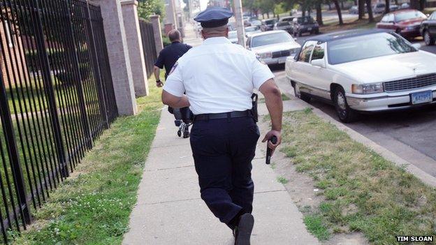 A Baltimore police officer runs with his gun drawn.