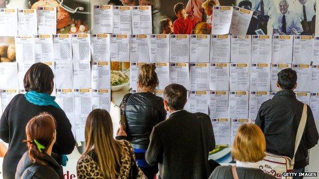 Job hunters looking at job ads in the job centre