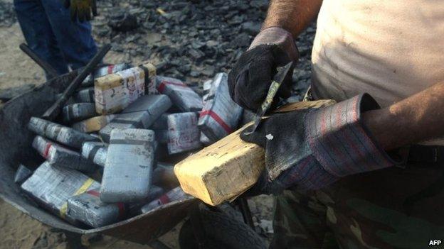 A man scrapes off coal from a brick of cocaine on 26 August 2014