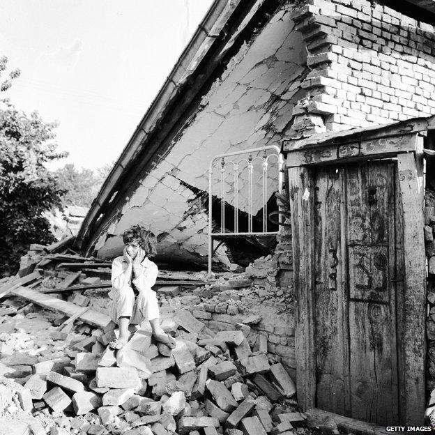 A young girl sits on the rubble of her home which was destroyed during the Skopje earthquake, 1963