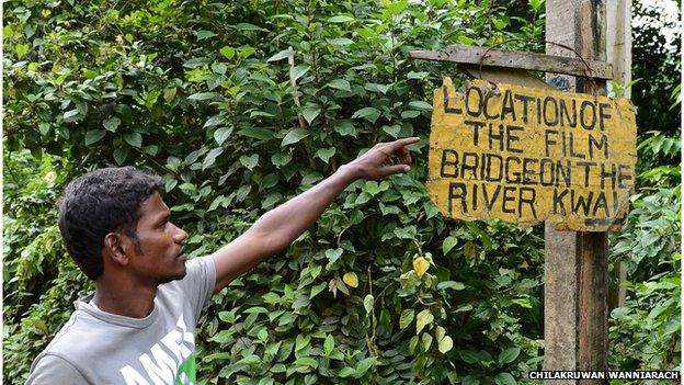 A Sri Lankan guide points to a sign at Kelani River at Kitulgala, where the film Bridge on the River Kwai was filmed. August 2014