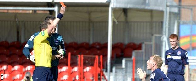 Referee Willie Collum shows a red card to Uros Celcer