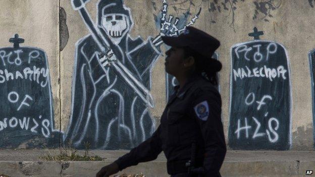 A police officer walks by gang graffiti depicting gang member deaths. April 14 2014