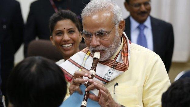 India's Prime Minister Narendra Modi (C) tries to play a soprano recorder before school children at a music class during a visit at Taimei Elementary School in Tokyo, September 1, 2014.