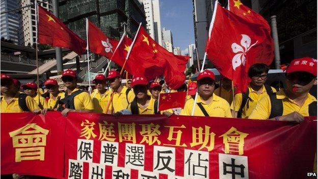 Pro-China protestors, opponents of the pro-democracy "Occupy Central" movement, march behind a banner reading "Reunited Families Support Group, Pro-Universal Suffrage, Make a First Step for Peaceful Universal Suffrage", in Central District, Hong Kong, China, 17 August 2014