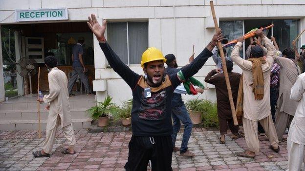 Pakistani protesters hold sticks and chant slogans after intruding into the state television building in Islamabad, Pakistan, Monday, Sept. 1, 2014.