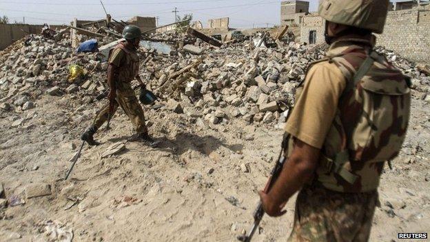 Pakistani soldiers stand near the debris of a house which was destroyed during a military operation against Taliban militants in the town of Miranshah in North Waziristan July 9, 2014.