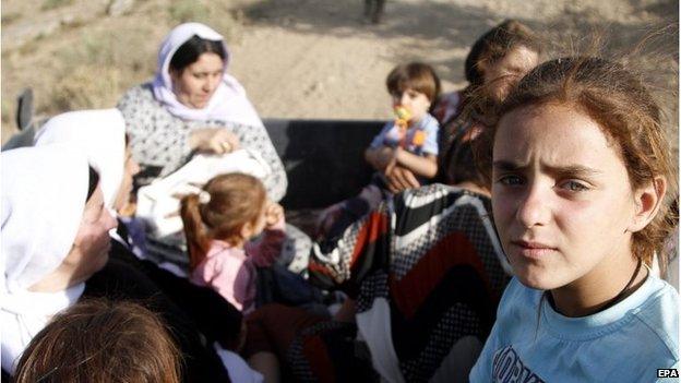 Yazidi refugees sit in a truck awaiting transfer as they flee from Iraq