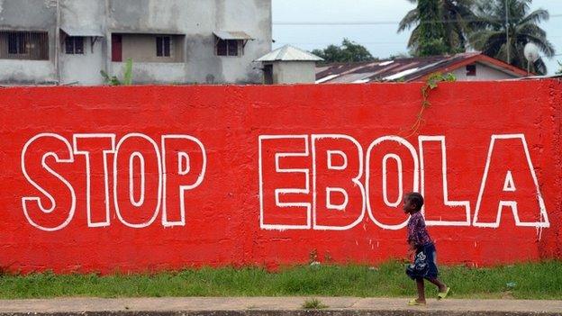 A girl walks past a slogan painted on a wall reading "Stop Ebola" in Monrovia - 31 August 2014