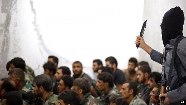 An Islamic State fighter gestures with a knife while addressing captured Syrian soldiers after the fall of Tabqa airbase in Raqqa province (27 August 2014)