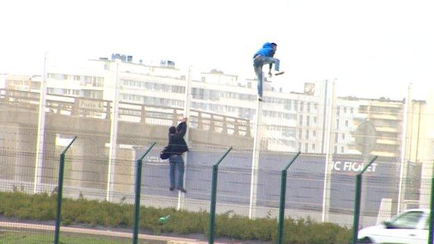 Migrants climbing fence