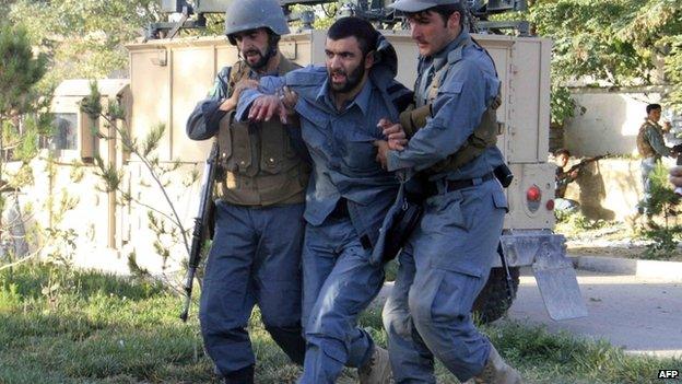 Afghan policemen help an injured comrade at the site of a suicide bomb attack in Ghazni Province 4 September 2014.