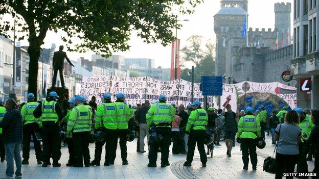 Police officers watch on from behind the protesters