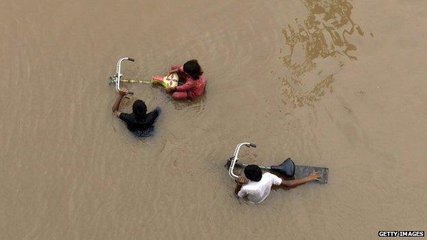 Pakistani residents wade through floodwaters following heavy rain in Lahore on September 4, 2014.