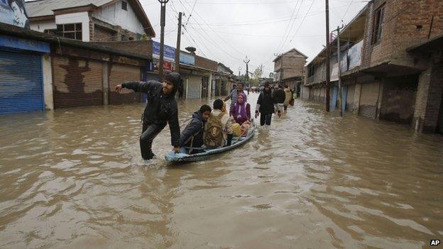 Kashmiris cross a flooded neighbourhood on a boat in Srinagar, India, Thursday, Sept. 4, 2014