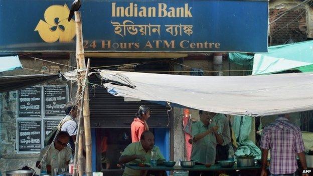 In this photograph taken on August 22, 2014, Indian customers eat at a roadside restaurant outside a bank in Calcutta