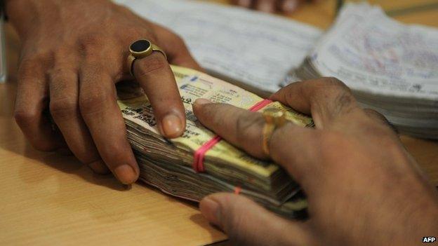 In this photograph taken on August 22, 2014, a customer deposits cash into his account at an Oriental Bank of Commerce branch in Mumbai.