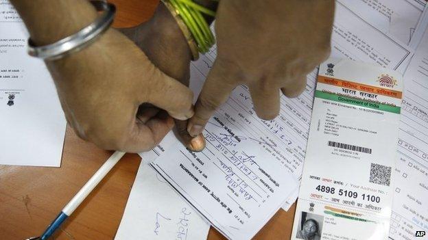 An Indian bank official takes the thumb impression of a woman before opening her account as part of a countrywide campaign to open millions of accounts for the poor in Delhi, India, Thursday, Aug. 28, 2014