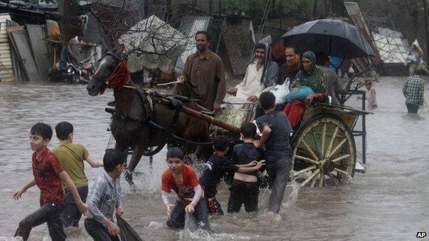 People make their way through a flooded road caused by heavy rain in Lahore, Pakistan, 5 September 2014