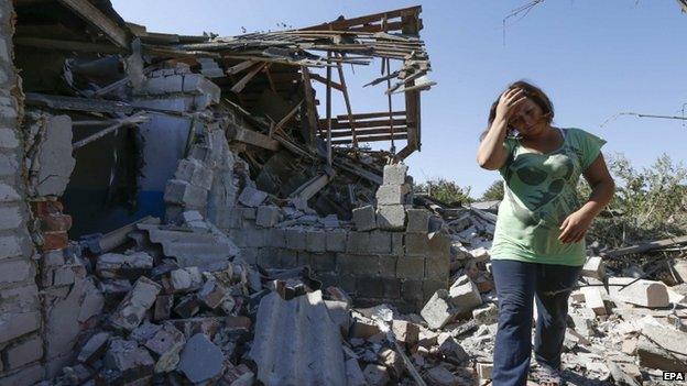 A woman walks at her destroyed house in the village of Kominternove, eastern Ukraine. Photo: 6 September 2014