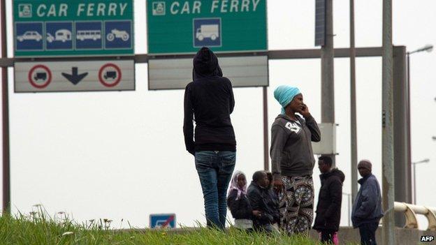 Migrants wait by side of road near Calais ferry port on 5 September 2014