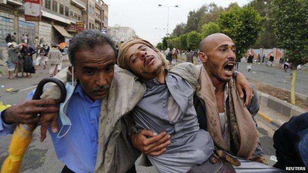 Houthis carry a fellow protester suffering from tear gas inhalation during clashes with riot police along the main road leading to the airport in Sanaa September 7