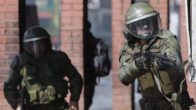 Police officers during clashes with hooded protesters after a march in Santiago on 7 September 2014