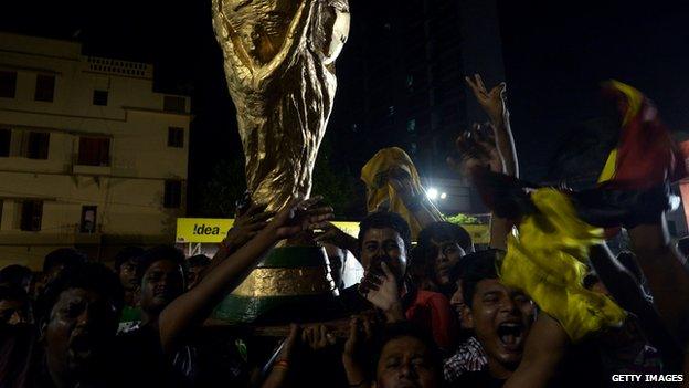 Indian German football team fans hold a World Cup trophy replica after Germany won the 2014 FIFA World Cup in Kolkata on July 14, 2014