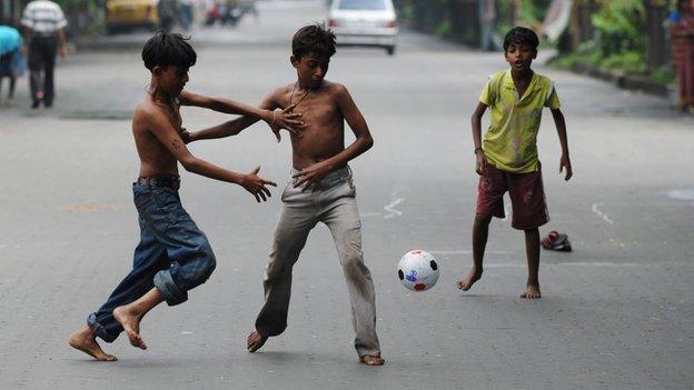 Indian boys play football in a near empty road in Calcutta