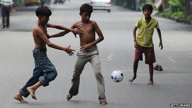 Indian boys play football in a near empty road in Calcutta