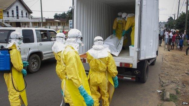 Liberian health care workers on an Ebola burial team collect the body of an Ebola victim in Paynesville on the outskirts of Monrovia, Liberia on 9 September 2014.