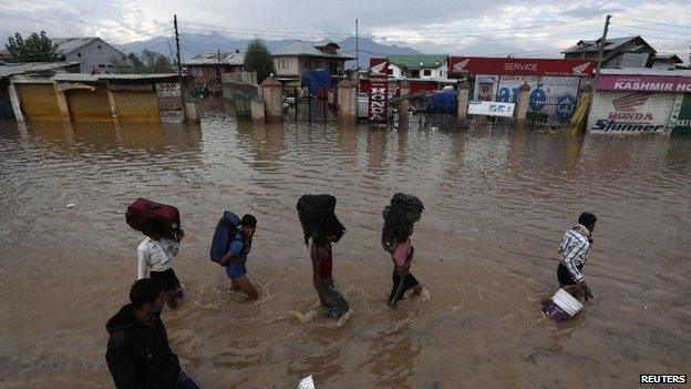 Kashmiri people wade through a flooded street as they move towards higher ground in Srinagar September 9, 2014