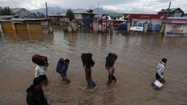 Kashmiri people wade through a flooded street as they move towards higher ground in Srinagar September 9, 2014