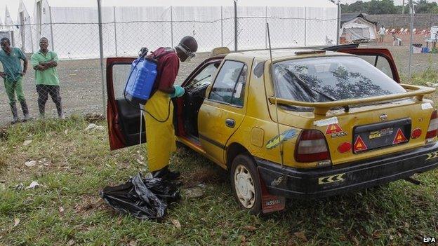 Liberian health worker disinfects taxi (9 September 2014)