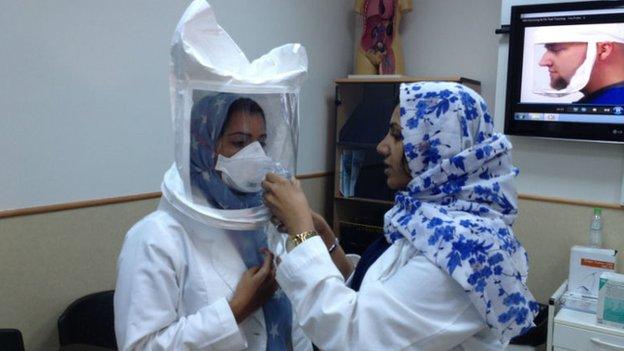 Health workers put on protective equipment in a Saudi hospital