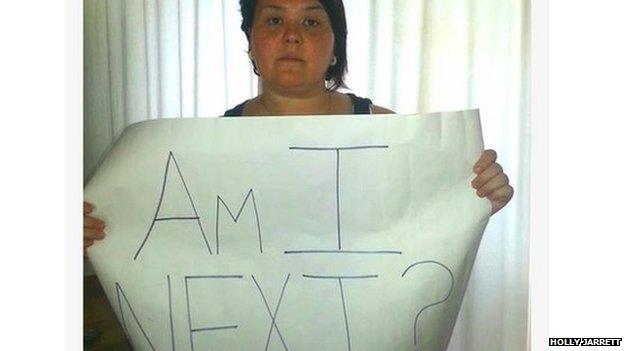 Woman holds "Am I next" sign?