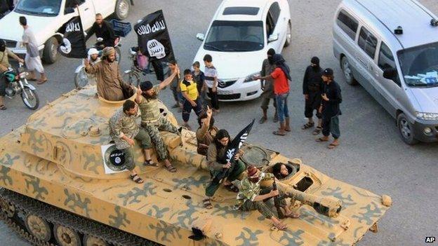 Islamic State fighters parade through the Syrian city of Raqqa in an armoured vehicle (30 June 2014)