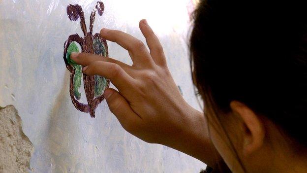 A young girl drawing on a wall